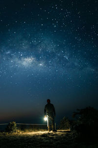 Rear view of man standing against sky at night