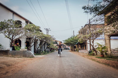 Rear view of man walking on street amidst buildings