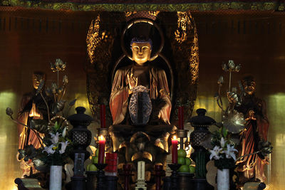 Statues in illuminated temple outside building
