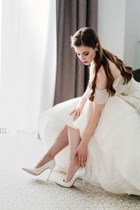 Side view of a smiling young woman sitting on floor