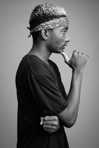 Side view of young man looking away against white background