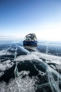 Ferris wheel by sea against sky during winter