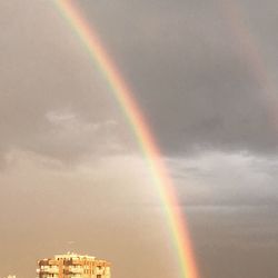 Low angle view of rainbow over building against sky