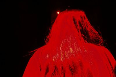 Close-up of red woman against black background