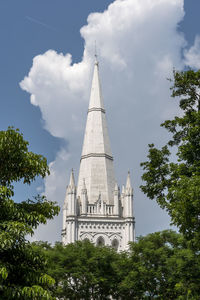 Low angle view of trees and building against sky