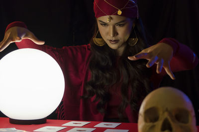 Female fortune teller with sphere and tarot cards at home