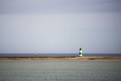 Lighthouse amidst sea against sky