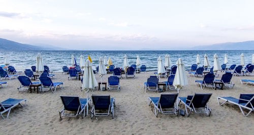 Chairs and tables on beach against sky during sunset