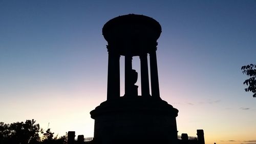 Low angle view of silhouette statue against sky at sunset