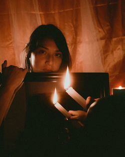 Portrait of young woman holding burning candle