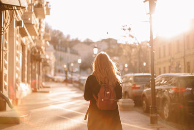 Rear view of teenage girl with backpack walking on street