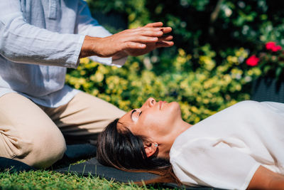 Woman in reiki spiritual healing session. reiki therapist holding hands above heart chakra