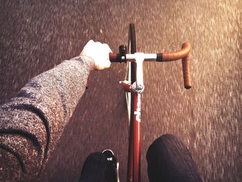 Close-up overhead view of cropped man riding bicycle on road