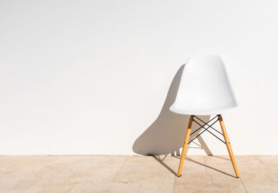 Empty chair on table against white wall at home