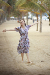 Full length of girl playing with arms raised standing at beach
