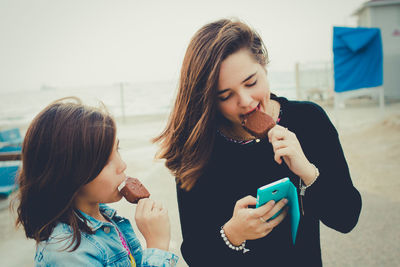 Happy mother with daughter while standing on mobile phone