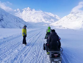 Rear view of people on snowcapped mountain against sky