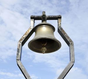 Low angle view of bell against cloudy sky