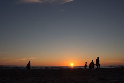 Silhouette people on beach at sunset