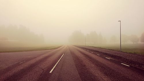 Empty road against sky during foggy weather