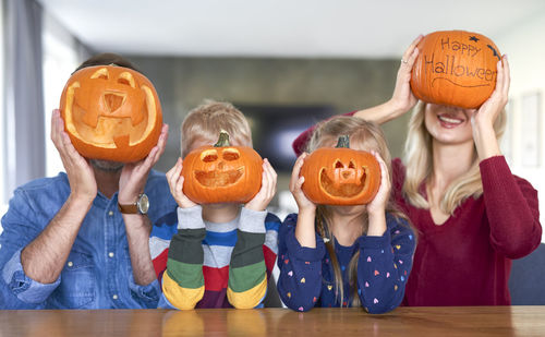 High angle view of friends with pumpkin on table