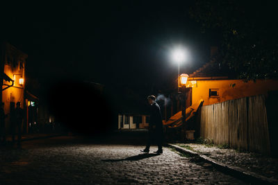 Full length of teenage boy walking on street at night