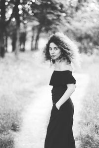 Portrait of woman standing against trees in forest