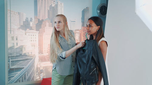 Young woman standing against window
