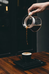 Man pouring coffee in cup on table