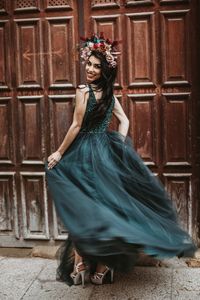 Portrait of young woman dancing against wall 