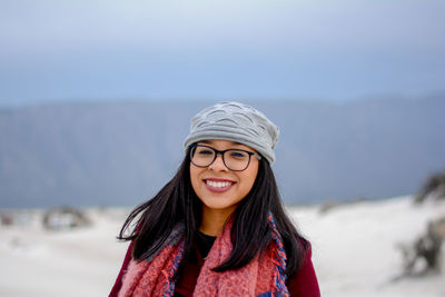 Portrait of smiling young woman standing on snow