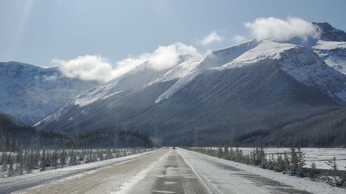 Road amidst snowcapped mountains against sky