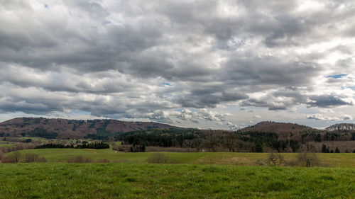 Scenic view of grassy field against cloudy sky