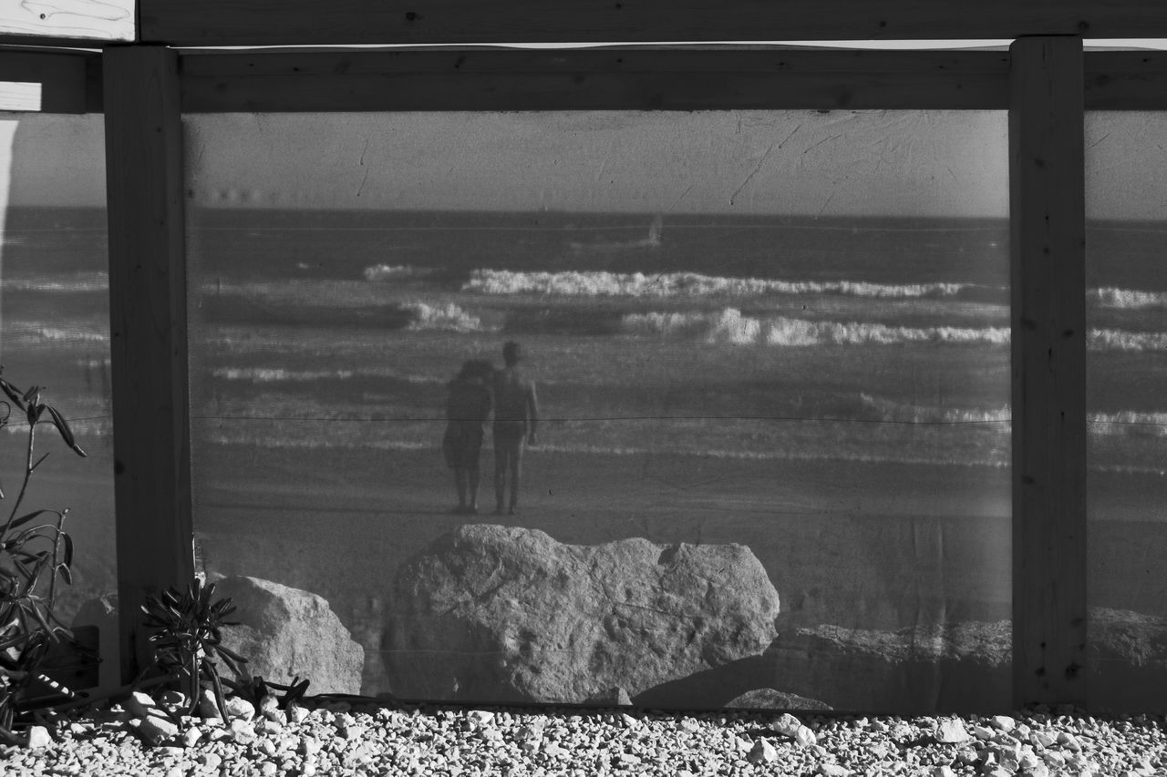 REAR VIEW OF PEOPLE STANDING AT BEACH