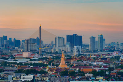 Modern buildings in city against sky during sunset