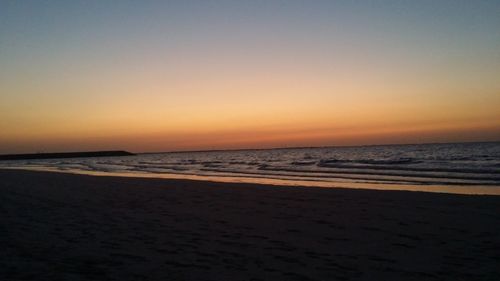 Scenic view of beach against clear sky during sunset