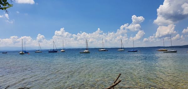 Sailboats moored in sea against blue sky