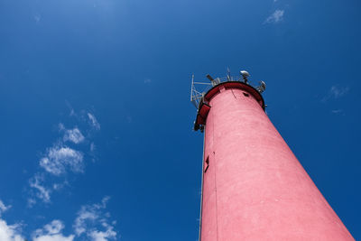 Low angle view of lighthouse by building against sky