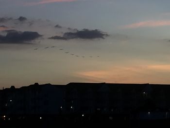 Silhouette buildings against sky at sunset