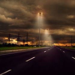 Cars on highway against cloudy sky