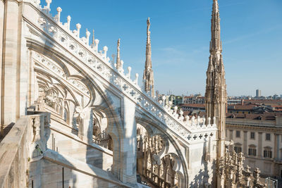 White statue on top of duomo cathedral and view to city of milan
