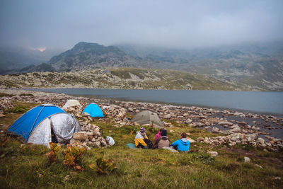 People sitting by tent against sky