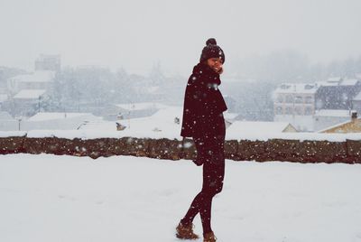 Woman walking on snow field against sky during winter