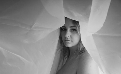 Portrait of shirtless woman below textile