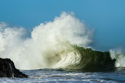 Scenic view of sea waves rushing towards shore against clear sky