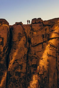 Low angle view of rocks on cliff against clear sky