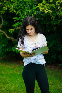 Teenage girl reading book at park