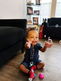 Portrait of cute boy playing with toy while sitting on sofa at home