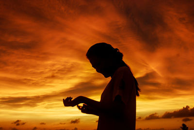 Silhouette man standing against orange sky