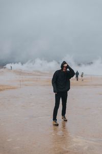 Full length of man standing at beach during stormy weather